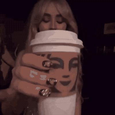 A Woman Is Holding A Starbucks Coffee Cup With A Face On It GIF