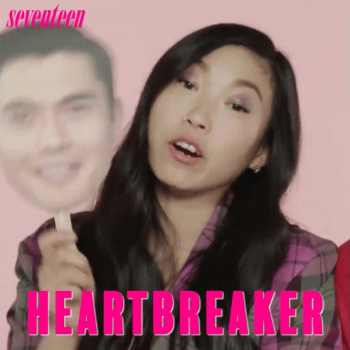 A Woman Is Holding A Stick With A Picture Of A Man On It And The Words Heartbreaker Written On It GIF