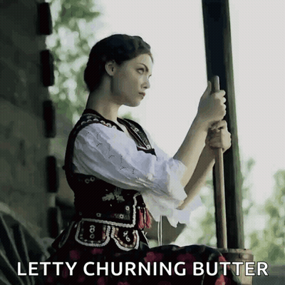 A Woman Is Holding A Stick With The Words Letty Churning Butter Behind Her GIF
