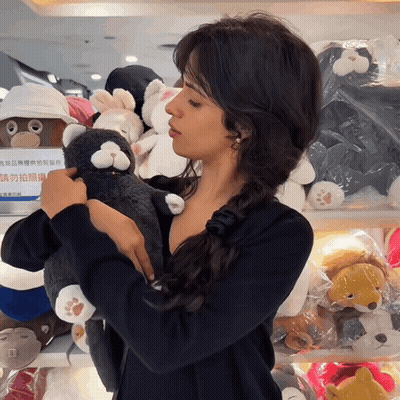 A Woman Is Holding A Stuffed Animal In Front Of A Sign That Says " 請 勿 拍照 " GIF