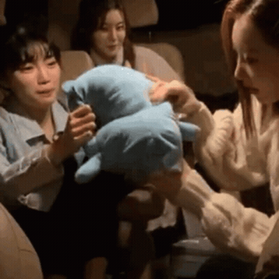 A Woman Is Holding A Stuffed Animal In Her Hands While Sitting In A Car . GIF