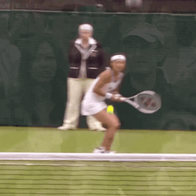 A Woman Is Holding A Tennis Racquet And Playing Tennis GIF