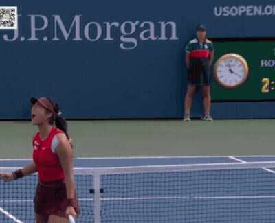 A Woman Is Holding A Tennis Racquet In Front Of A Sign For The Us Open GIF