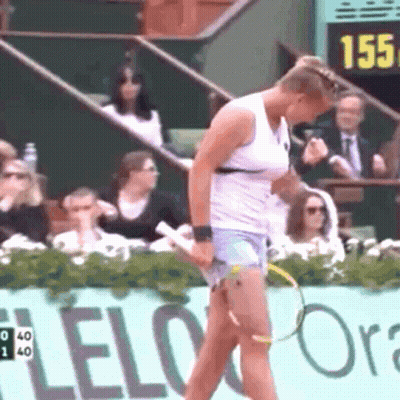 A Woman Is Holding A Tennis Racquet In Front Of A Sign That Says Lelo Ora GIF