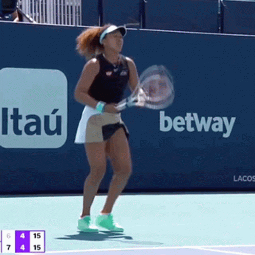 A Woman Is Holding A Tennis Racquet In Front Of An Advertisement For Itaú GIF