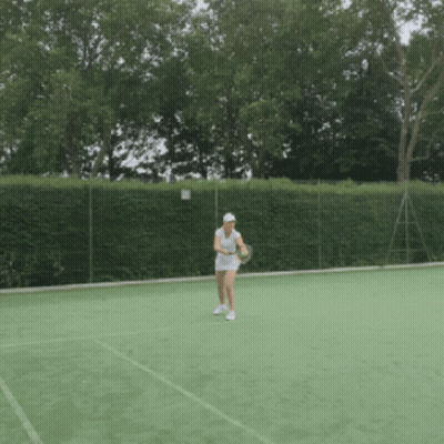 A Woman Is Holding A Tennis Racquet On A Court GIF
