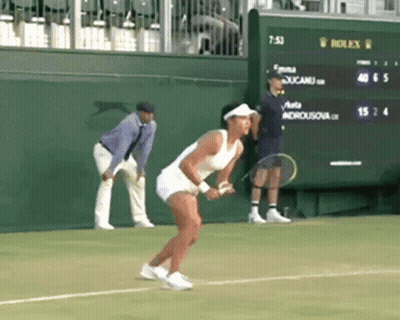 A Woman Is Holding A Tennis Racquet On A Tennis Court In Front Of A Scoreboard That Says Rolex On It GIF