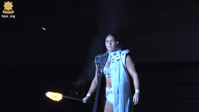 A Woman Is Holding A Torch In Front Of A Sign That Says Fpw Mg GIF