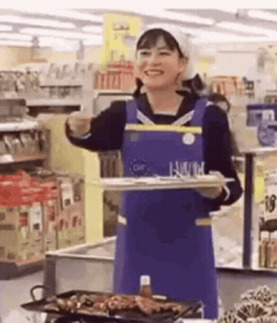 A Woman Is Holding A Tray Of Food In A Supermarket . GIF