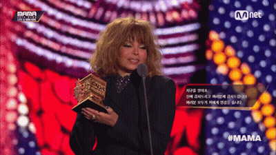 A Woman Is Holding A Trophy And Speaking Into A Microphone At A Mama Event GIF