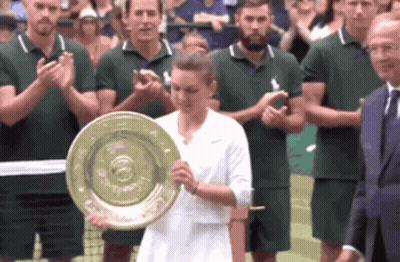 A Woman Is Holding A Trophy In Front Of A Crowd Of People GIF
