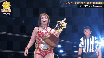 A Woman Is Holding A Trophy In Front Of A Referee And The Words #Jpw_mg Are Above Her GIF