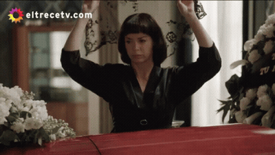A Woman Is Holding A Veil Over A Red Coffin With Eltrecetv.com Written On The Bottom GIF