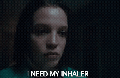 A Woman Is Holding An Inhaler In Her Hand In Front Of Her Face . GIF