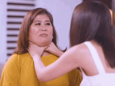 A Woman Is Holding Another Woman 'S Neck In A Room . GIF