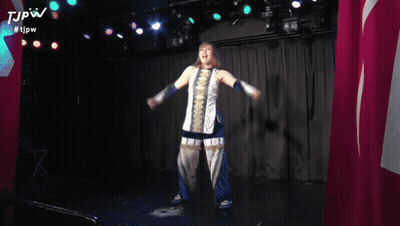 A Woman Is Holding Her Arms Up In The Air While Wearing A Scarf And Blue Gloves . GIF