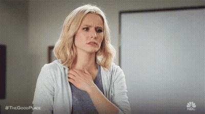 A Woman Is Holding Her Chest In Pain While Standing In A Classroom . GIF