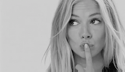 A Woman Is Holding Her Finger To Her Lips And Making A Shhh Gesture . GIF