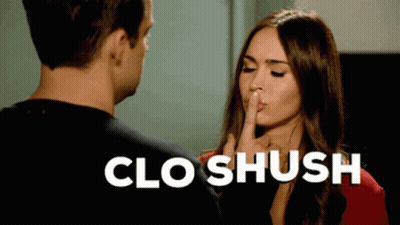 A Woman Is Holding Her Finger To Her Lips While A Man Looks On And The Words Clo Shush Are Above Her GIF
