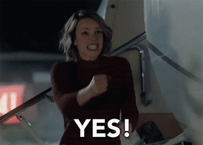 A Woman Is Holding Her Fist In The Air And Says Yes GIF