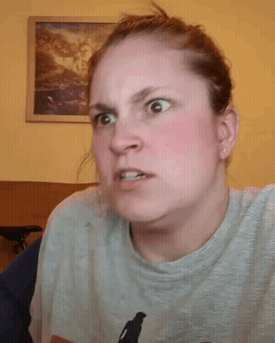 A Woman Is Holding Her Hair In A Ponytail While Wearing A Gray Shirt . GIF
