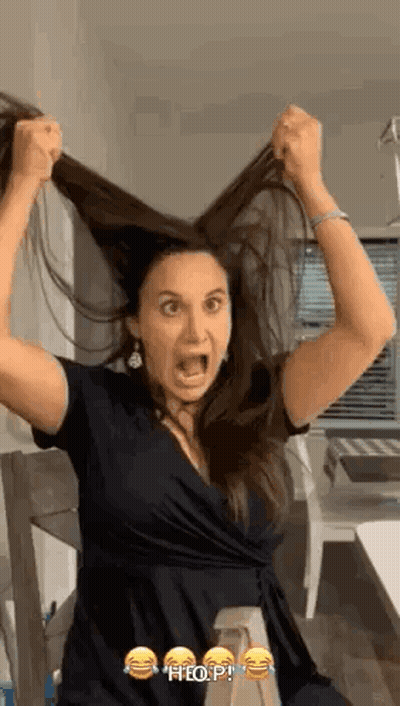 A Woman Is Holding Her Hair In The Air With Her Mouth Open . GIF