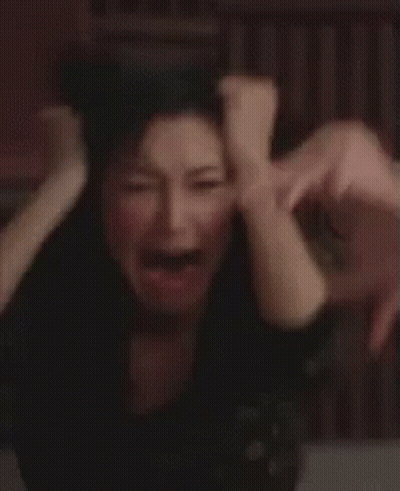 A Woman Is Holding Her Head With Her Hands While Crying . GIF