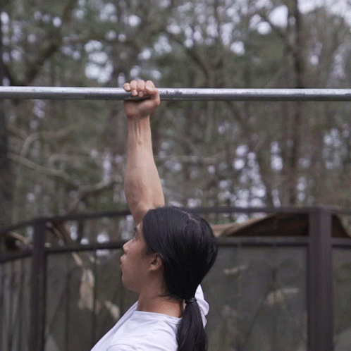A Woman Is Holding Onto A Metal Bar With Her Hand GIF