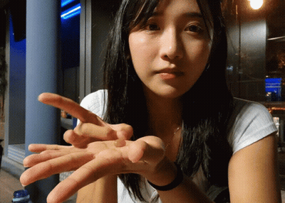 A Woman Is Holding Something In Her Hand And Pointing At It GIF
