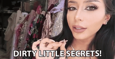 A Woman Is Holding Something In Her Hand In Front Of A Row Of Clothes And Says `` Dirty Little Secrets ! '' GIF