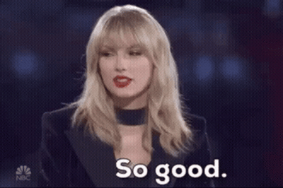 A Woman Is Holding Two Hot Dogs In A Pair Of Tongs And Saying So Good . GIF