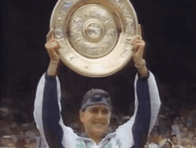 A Woman Is Holding Up A Trophy That Says ' Winner ' On It GIF