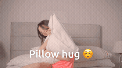 A Woman Is Hugging A Pillow With The Words Pillow Hug Written Below Her GIF