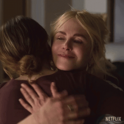 A Woman Is Hugging Another Woman In A Room . GIF