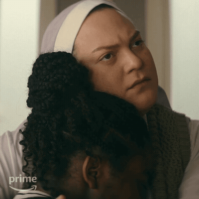 A Woman Is Hugging Another Woman Who Is Wearing A Headband That Says Prime GIF