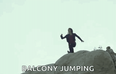 A Woman Is Jumping Off A Rock While A Man Watches . GIF