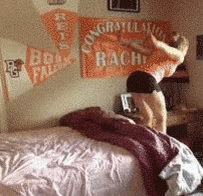 A Woman Is Jumping On A Bed In Front Of A Congratulations Bach Banner GIF