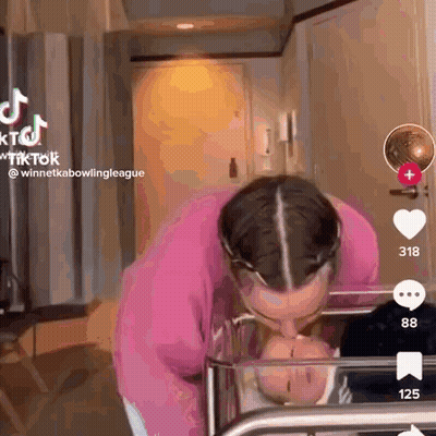 A Woman Is Kissing A Baby In A Crib In A Room . GIF