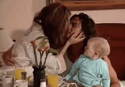 A Woman Is Kissing A Baby On The Cheek . GIF