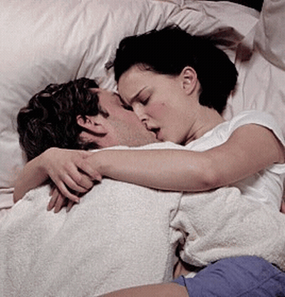 A Woman Is Kissing A Man In Bed GIF