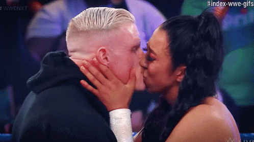 A Woman Is Kissing A Man On The Cheek In A Wrestling Match GIF
