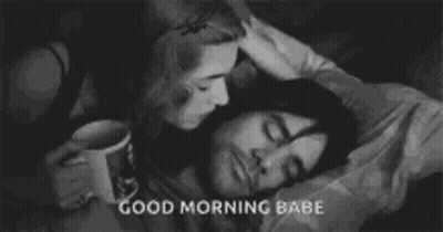 A Woman Is Kissing A Man On The Forehead While He Sleeps In Bed . GIF