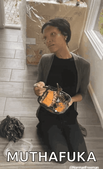 A Woman Is Kneeling On The Floor Holding A Container Of Food That Says Muthafuka On The Bottom GIF