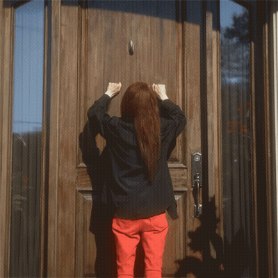 A Woman Is Knocking On A Door With Her Fist GIF