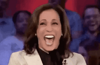 A Woman Is Laughing In Front Of A Crowd Of People . GIF