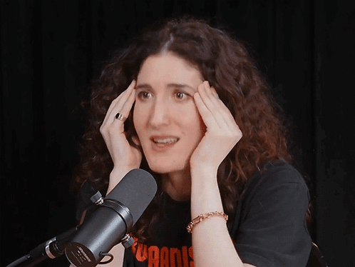 A Woman Is Laughing In Front Of A Microphone That Says ' Sven ' On It GIF