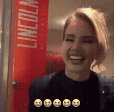 A Woman Is Laughing In Front Of A Red Lincoln Sign GIF