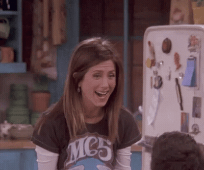 A Woman Is Laughing In Front Of A Refrigerator . GIF