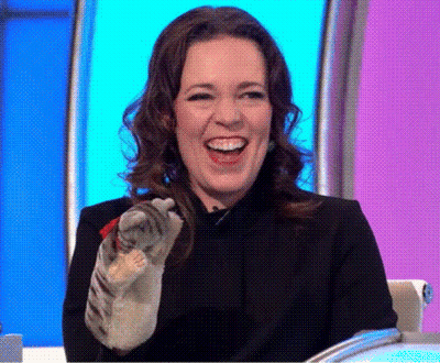 A Woman Is Laughing While Holding A Cat In Her Hand On A Television Show . GIF