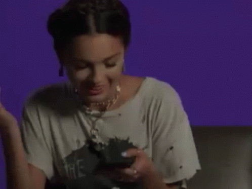 A Woman Is Laughing While Holding A Cell Phone . GIF